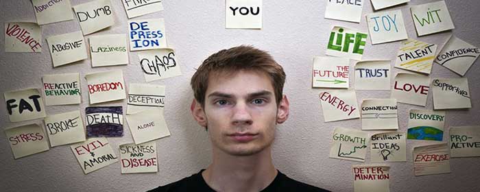 young man surrounded by post it notes quoting feelings