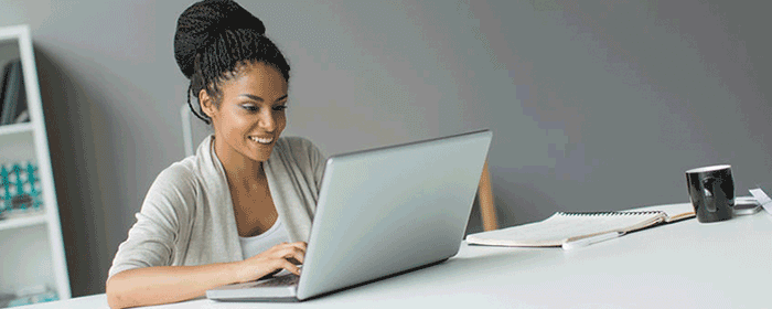smiling female tying on a laptop in a clean workspace