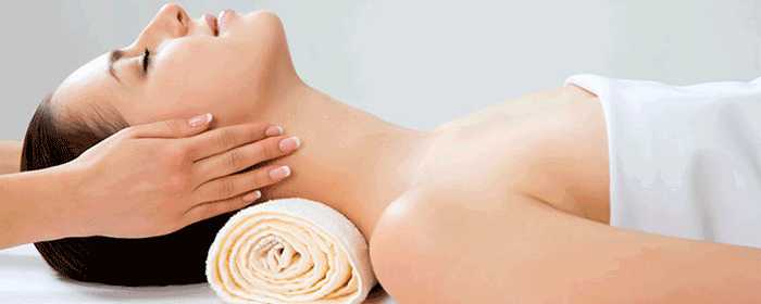female receiving a neck massage, while her head rests on a rolled up towel